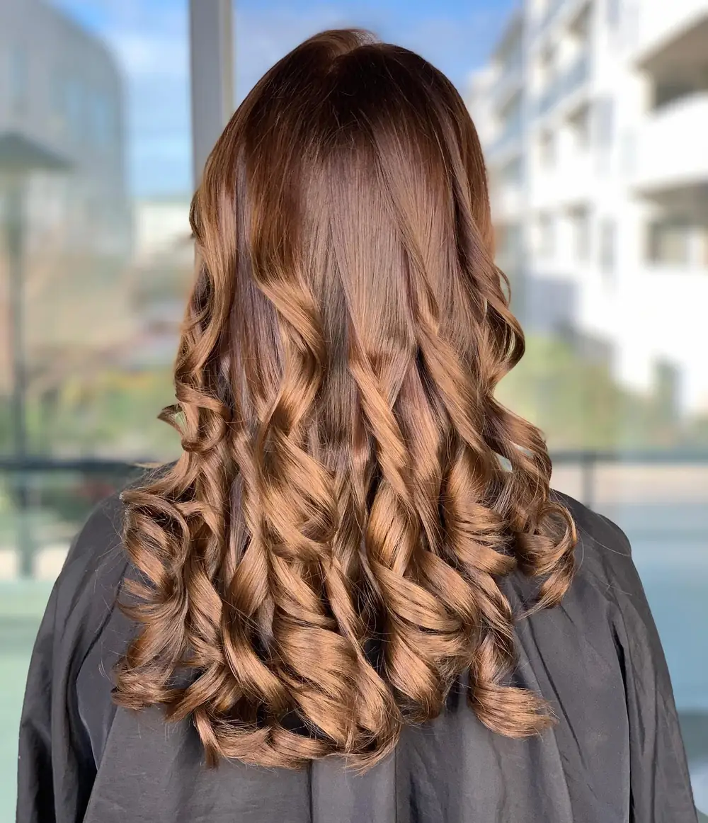 Coloration caramel dorée sur cheveux longs bouclés, vue de dos, réalisée par Julie DreamColor