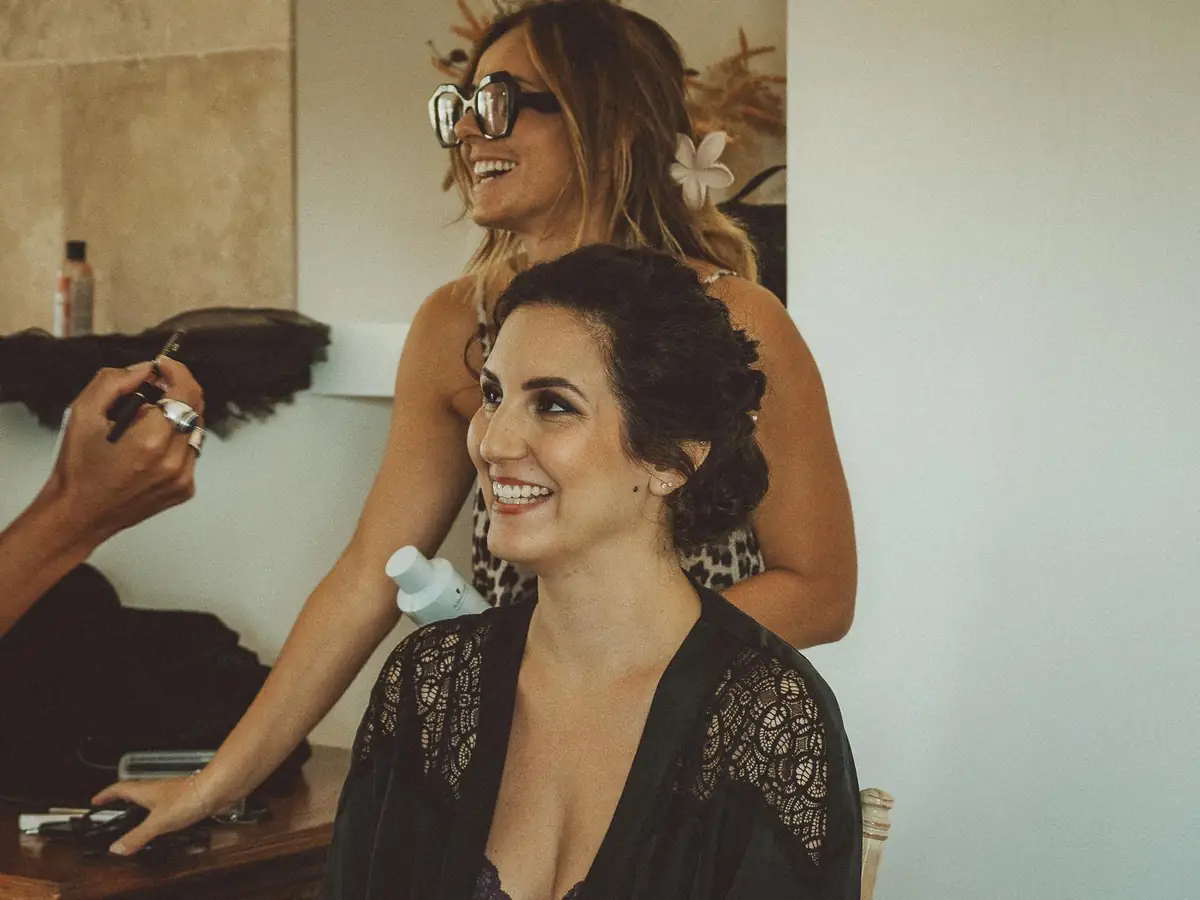 Julie DreamColor réalise le chignon d'une mariée brune le matin du mariage, pendant sa mise en beauté avec la maquilleuse