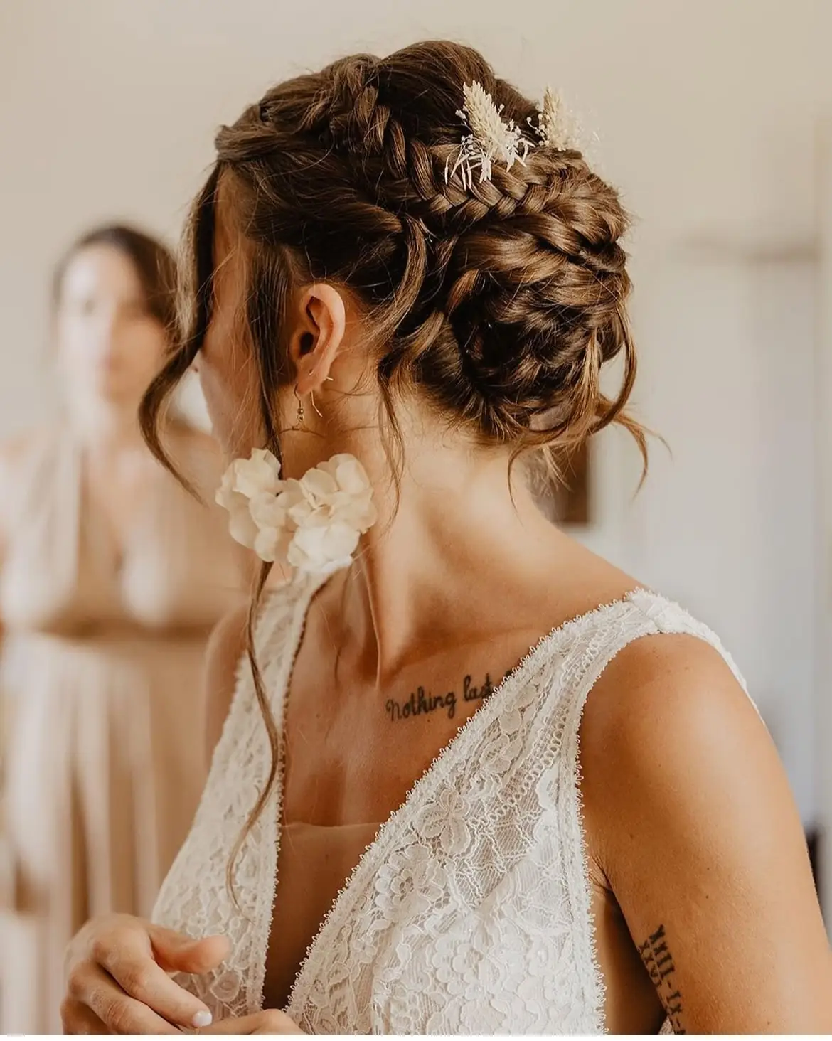 Mariée de dos avec un chignon tressé orné d'une fleur blanche, coiffure réalisée par Julie DreamColor à Bordeaux